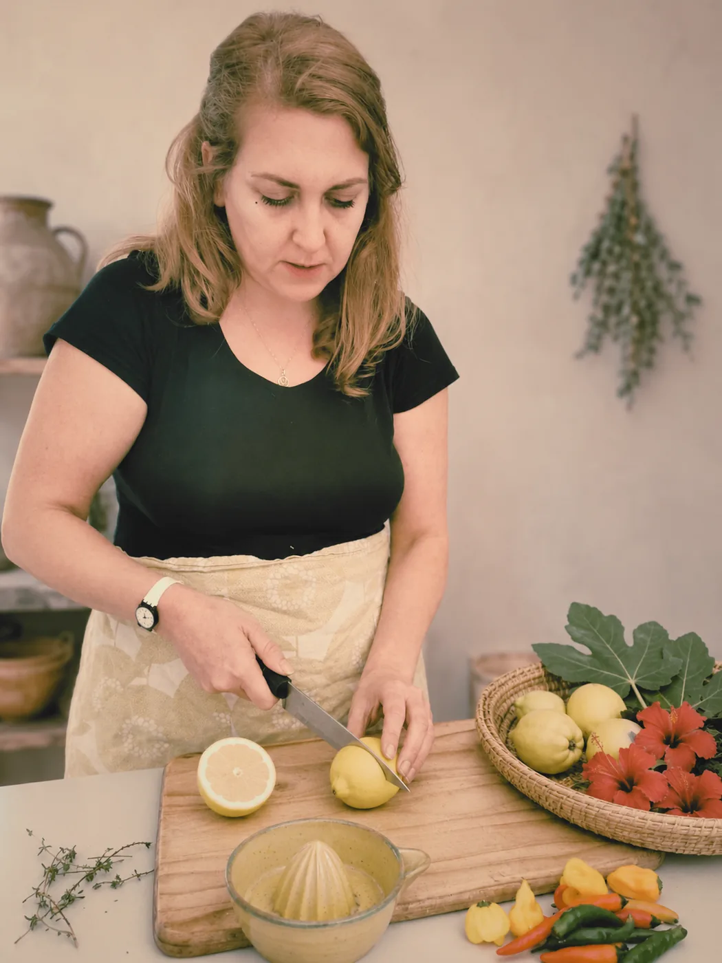 Julie slicing a lemon at a wooden chopping board with a bowl of citrus zest beside her