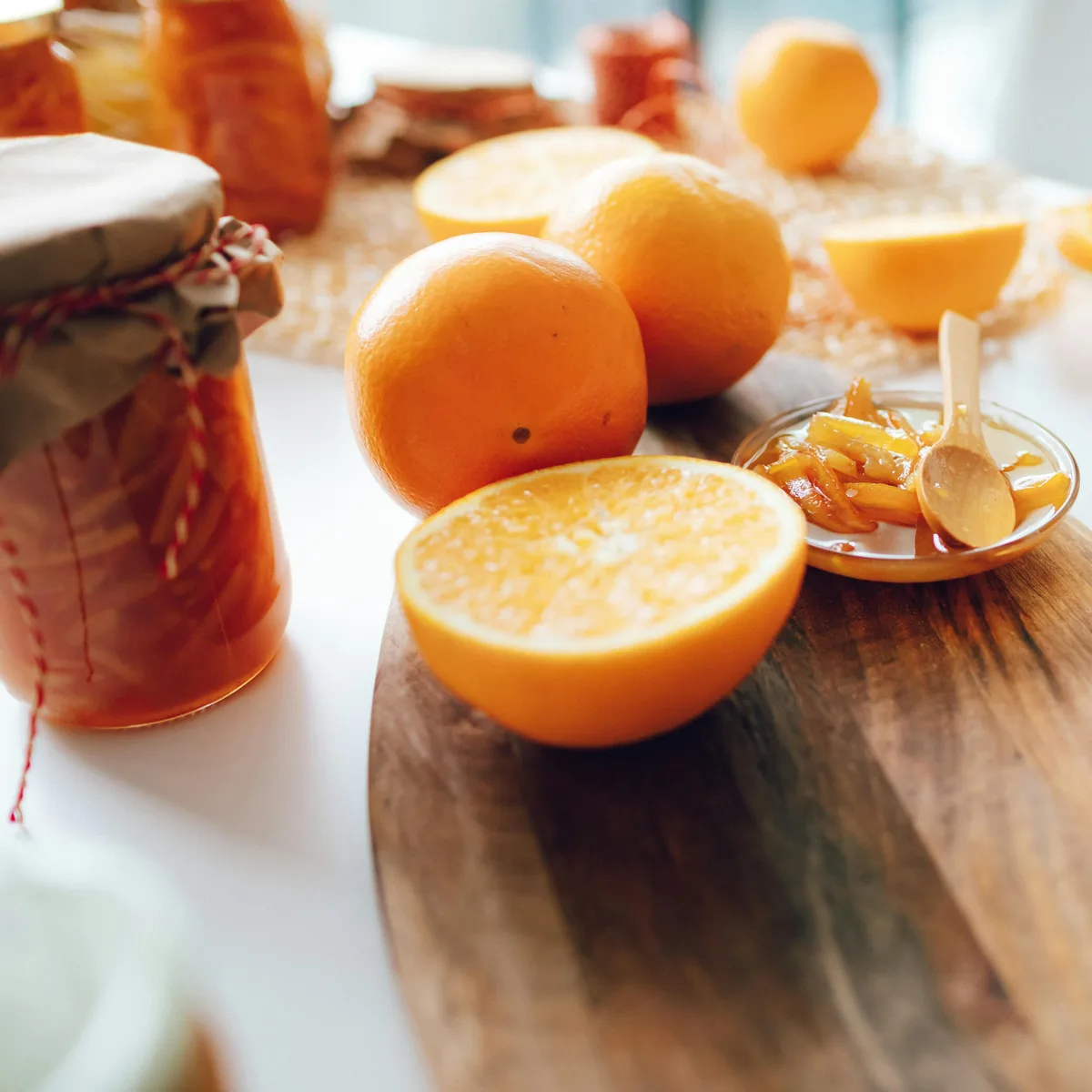 Halved oranges and jars of marmalade on a wooden board